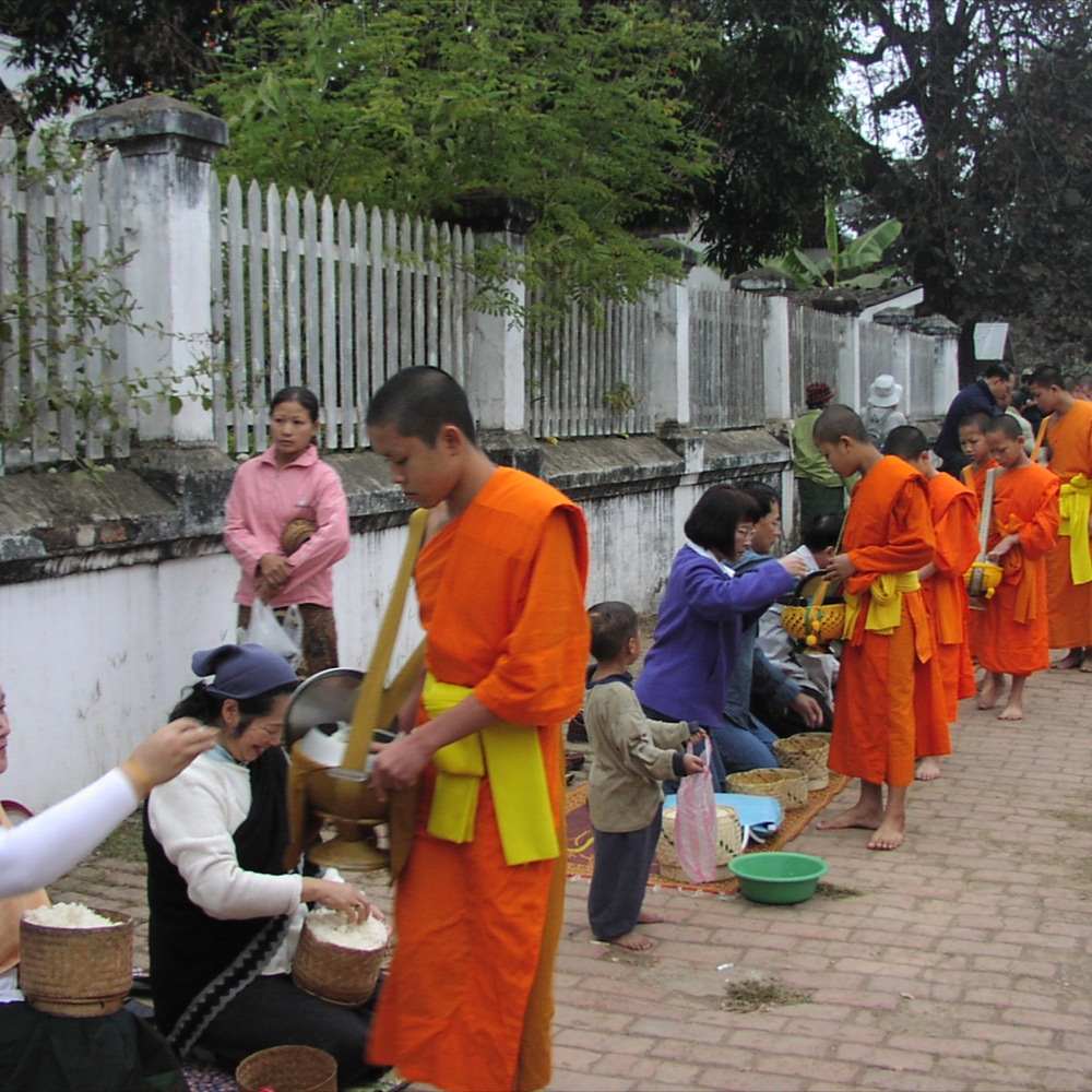 托鉢に並ぶ僧侶とお供え物をする人々